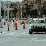 Rajdowy samochód mija pachołki w mieście przy dopingu kibiców