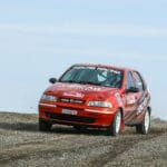 Czerwony Fiat Palio w akcji na szutrowym odcinku rajdowym