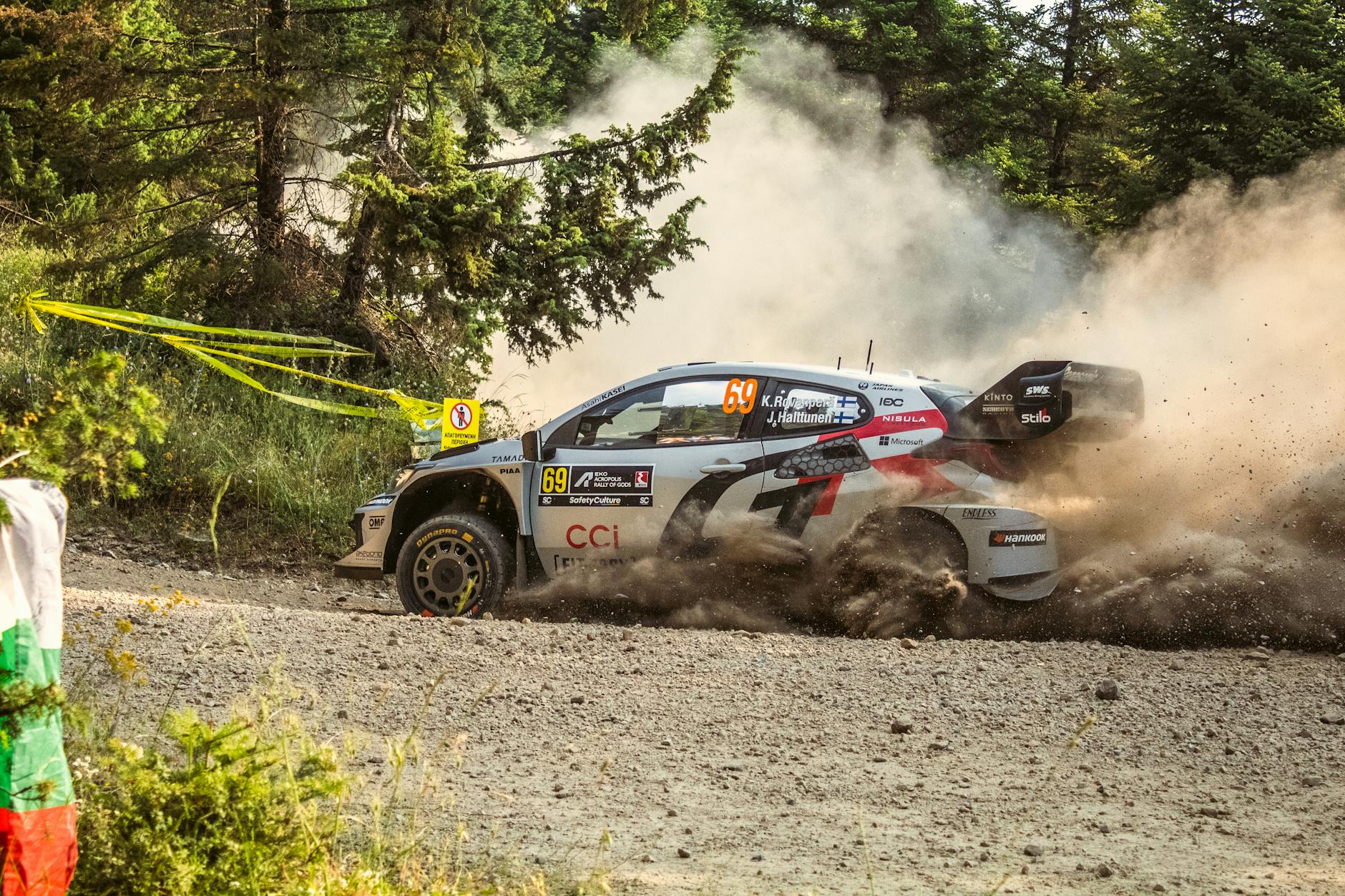 Samochód WRC pędzi po zakurzonej leśnej drodze w Grecji