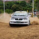 Rajdówka driftująca na szutrowej trasie, wzbijając kurz w WRC